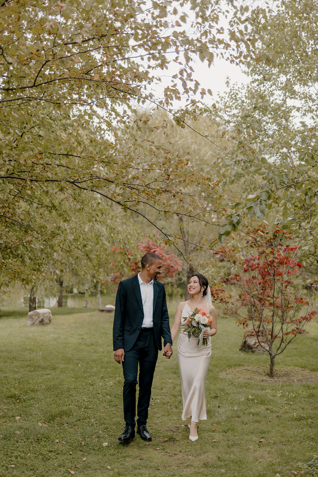 Stunning bride and groom walk in the garden together 