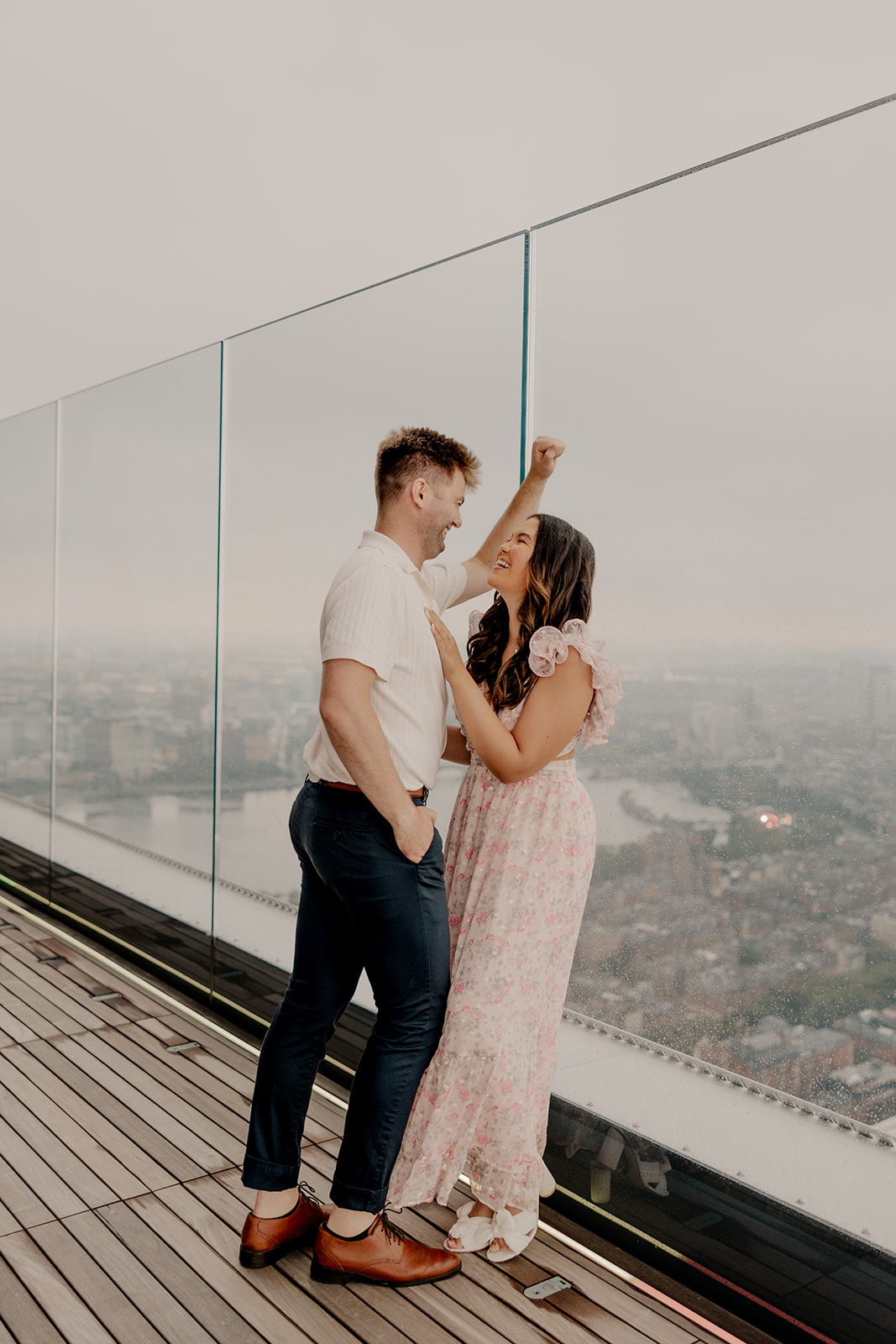 couple poses with the city of Boston in the background learn how to prepare for Boston engagement photoshoot here