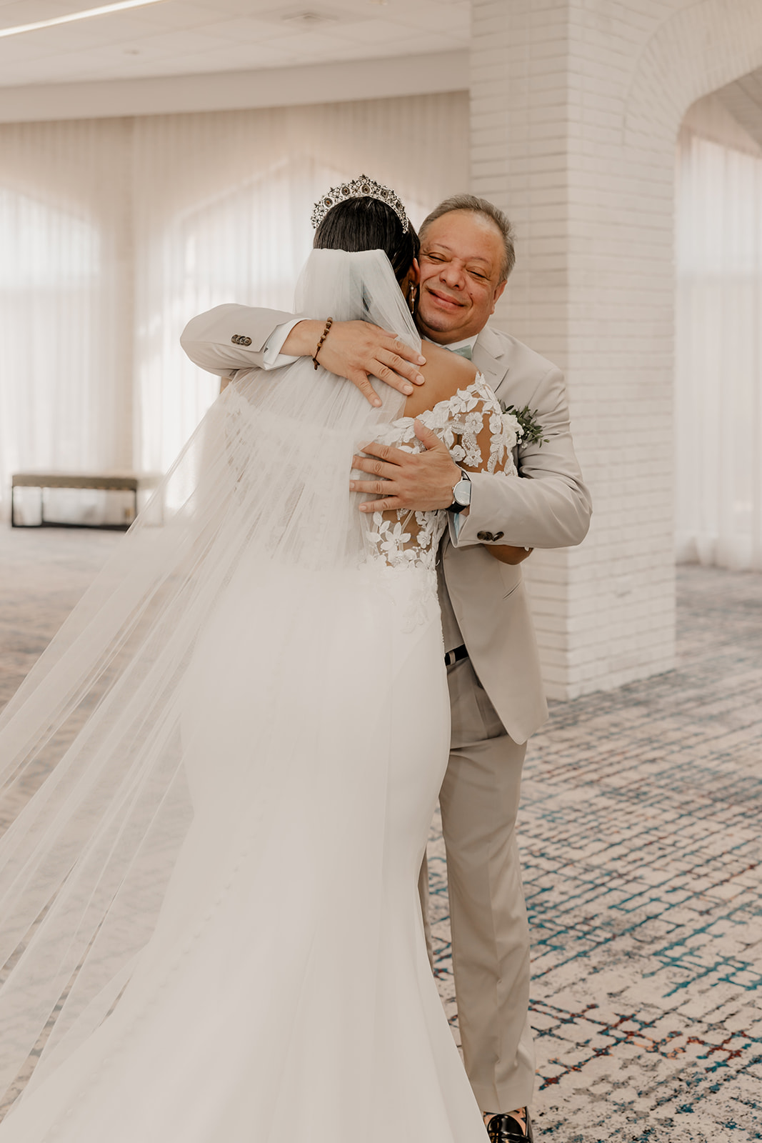 father shares a hug with his stunning daughter during their first look wedding photos