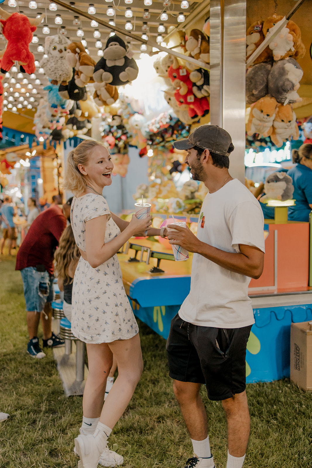 couple walk the fairgrounds taking candid style engagement photos 