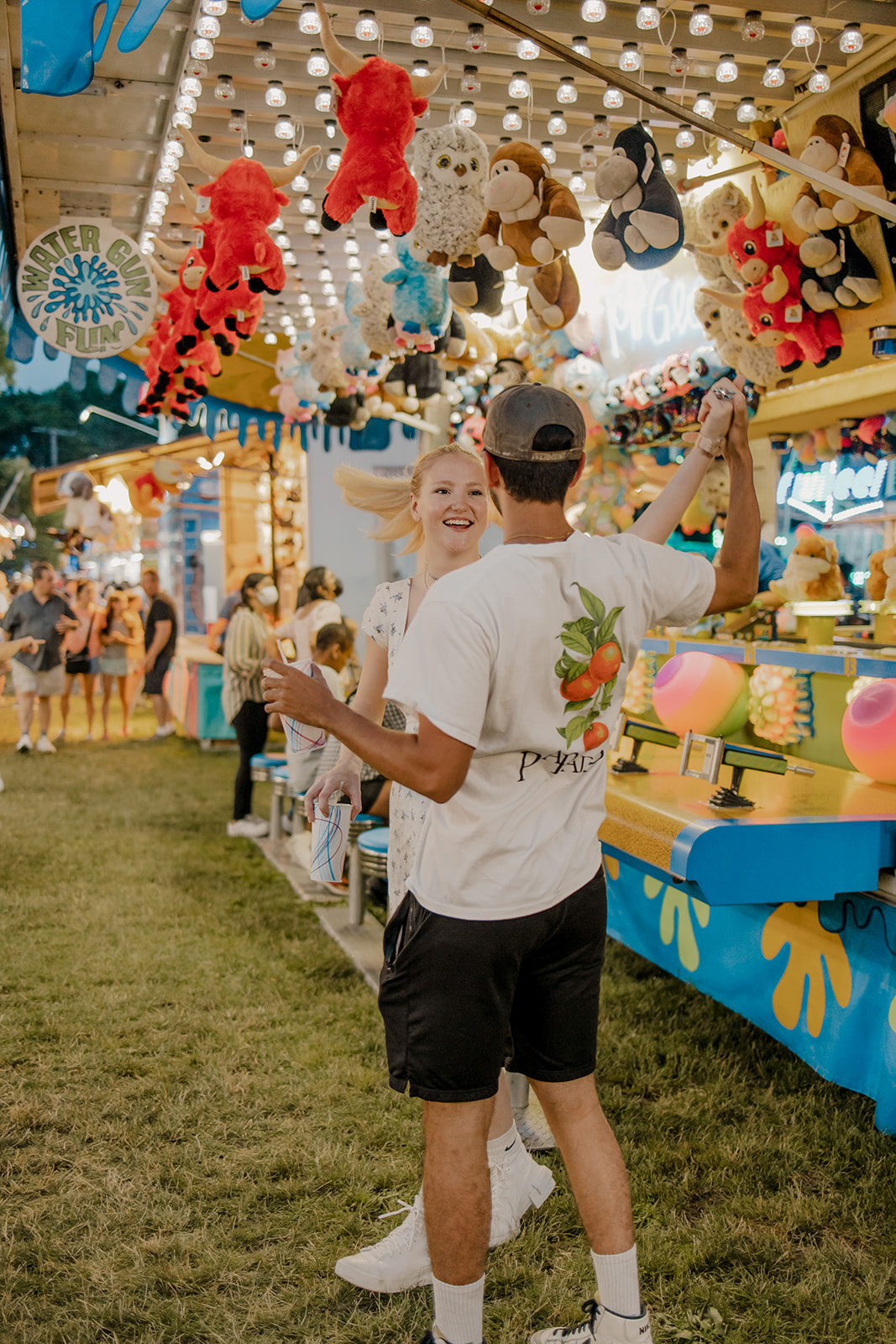 couple walk the fairgrounds taking candid style engagement photos 