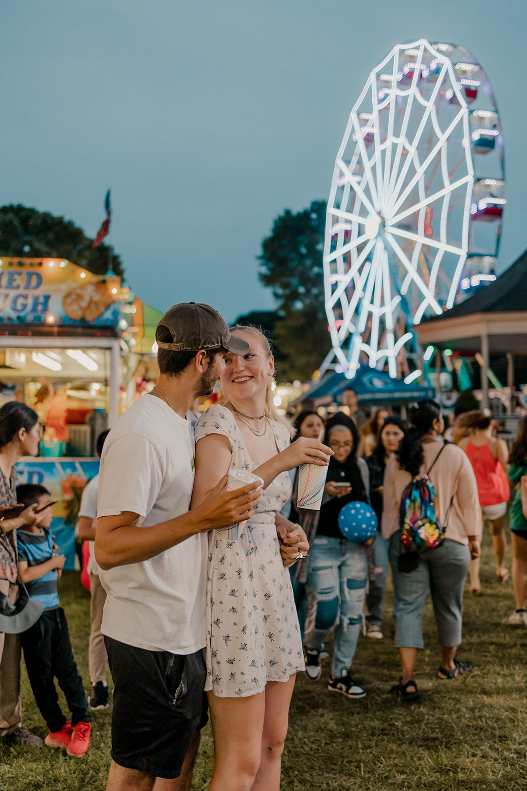 couple walk the fairgrounds taking candid style engagement photos 