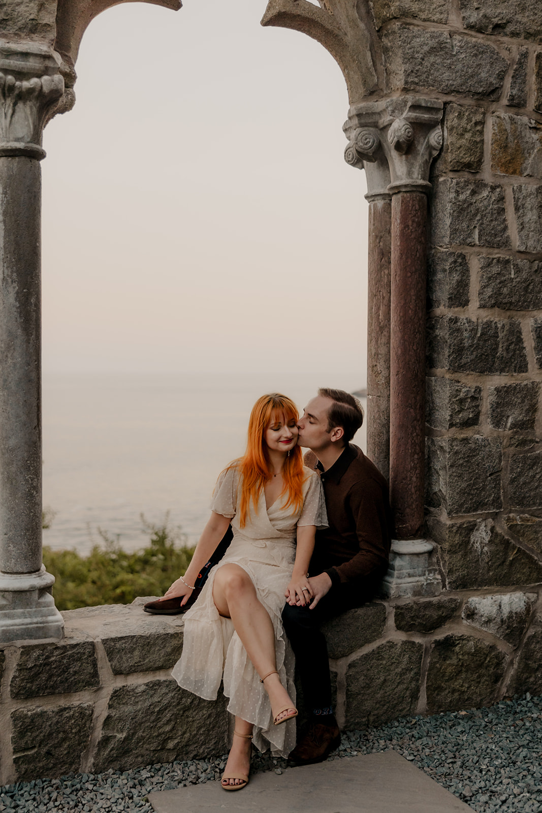 beautiful couple pose inside the Hammond castle overlooking the sea during their Massachusetts engagement photoshoot