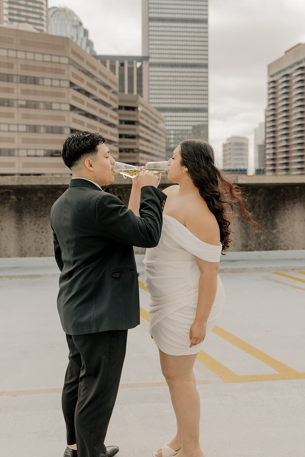 Boston engagement photos share champagne with the downtown skyline in the background