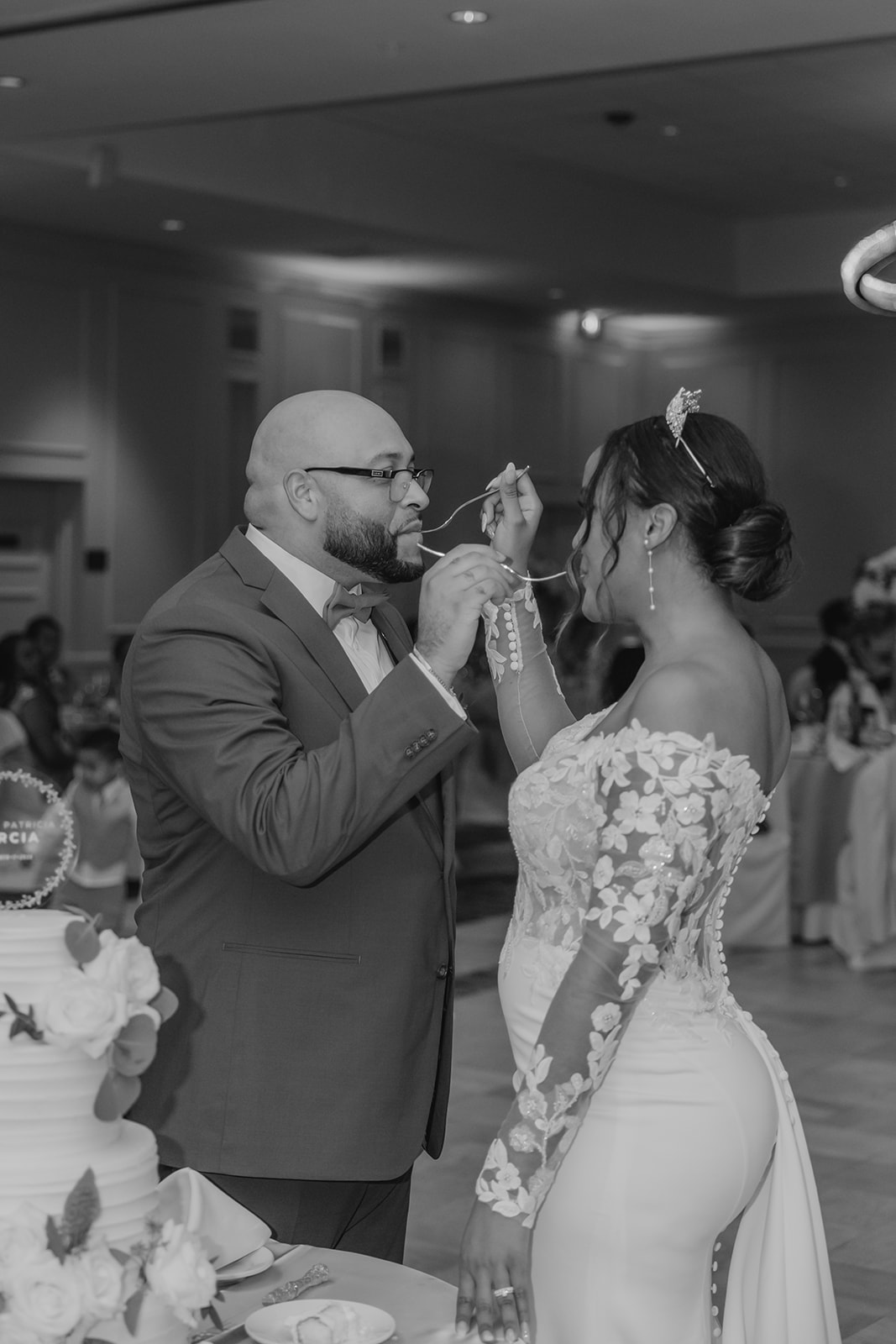 bride and groom share a bite of cake with each other after they cut their cake together 