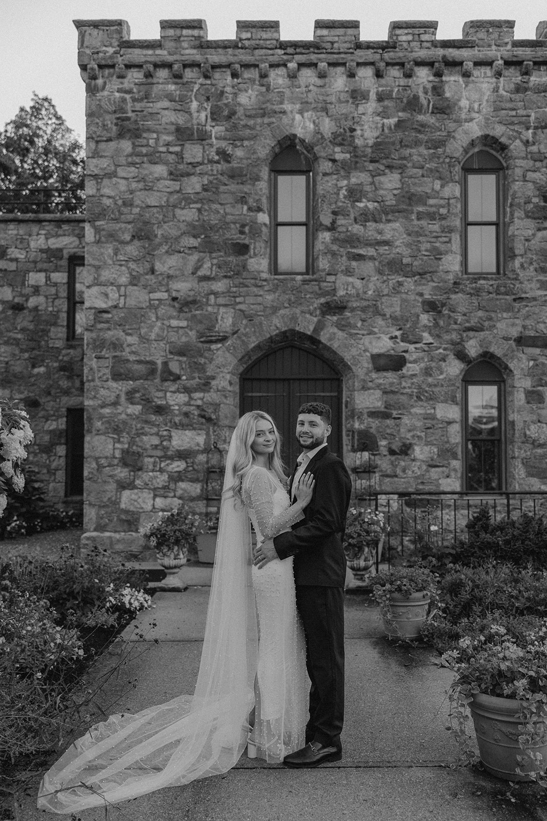 bride and groom pose in front of the castle 