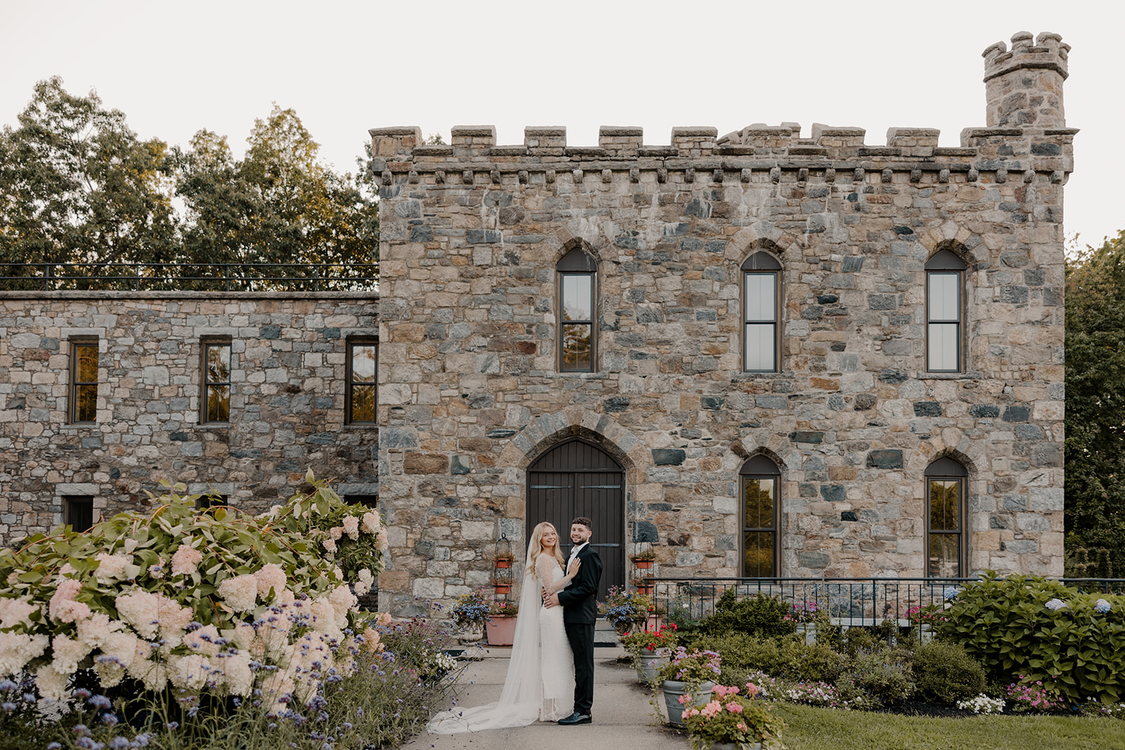 bride and groom pose in front of a castle for their day-after wedding session.