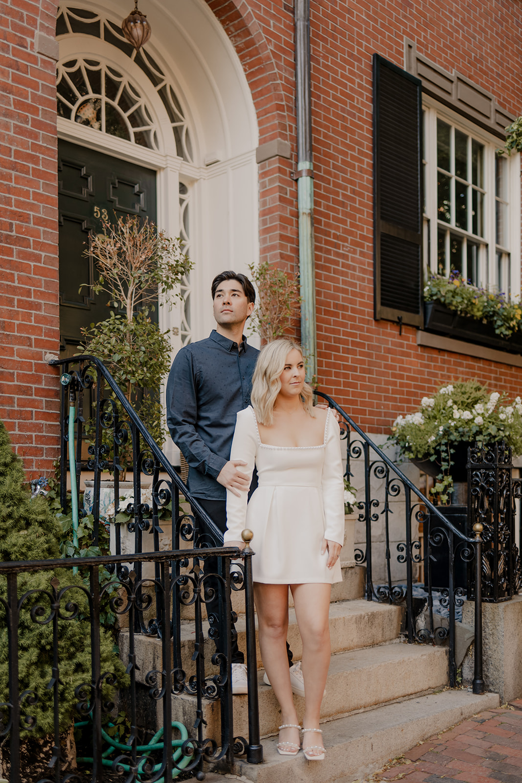 Couple pose on stairs with a classic brick home behind them