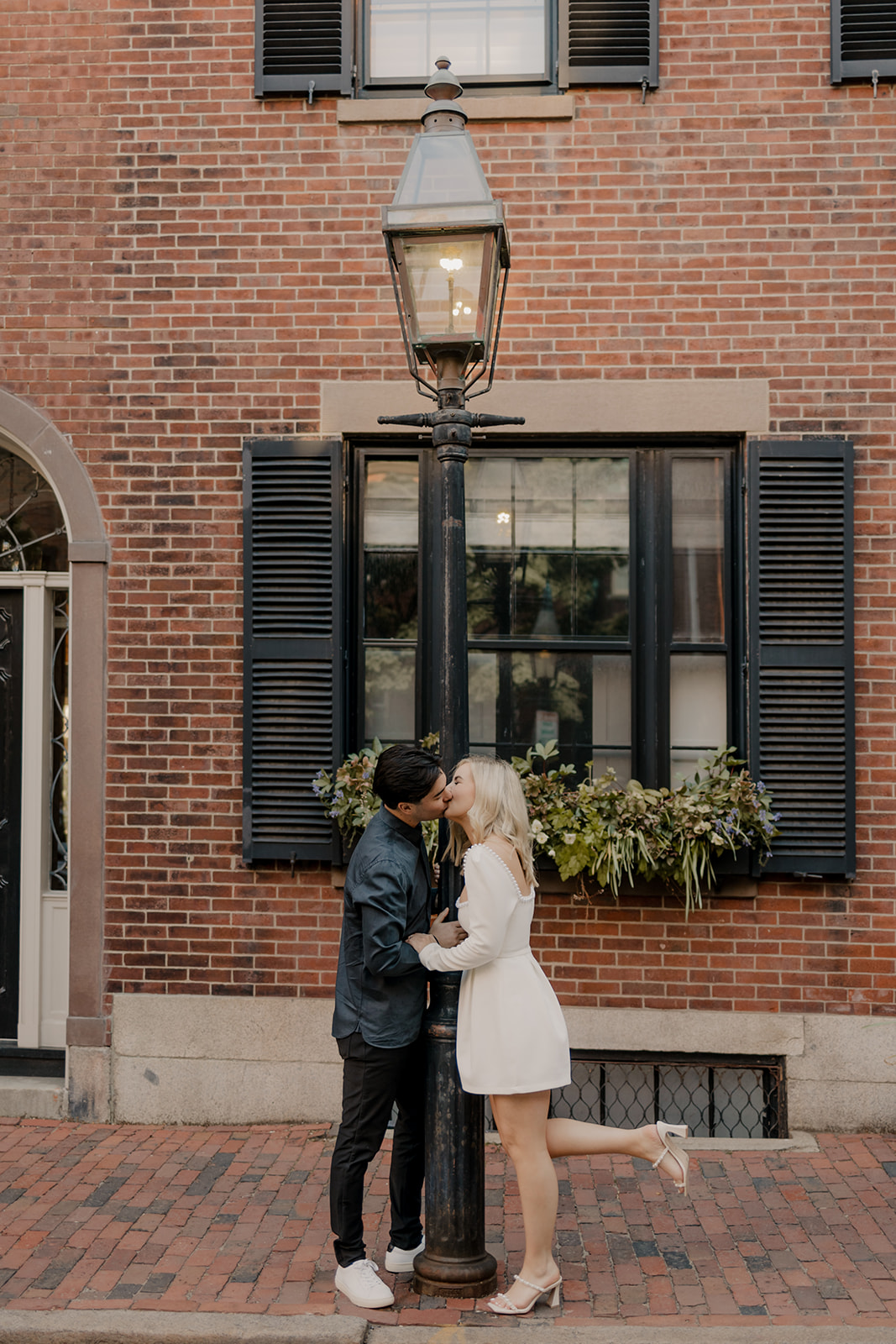 Couple pose on stairs with a classic brick home behind them