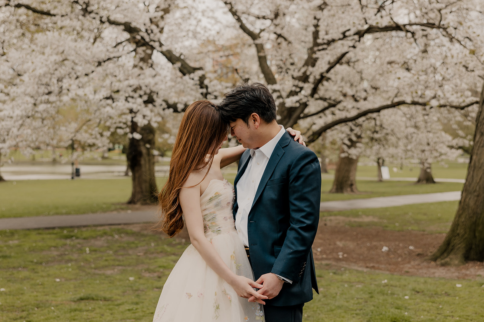 Beautiful couple pose together with a blooming tree behind them