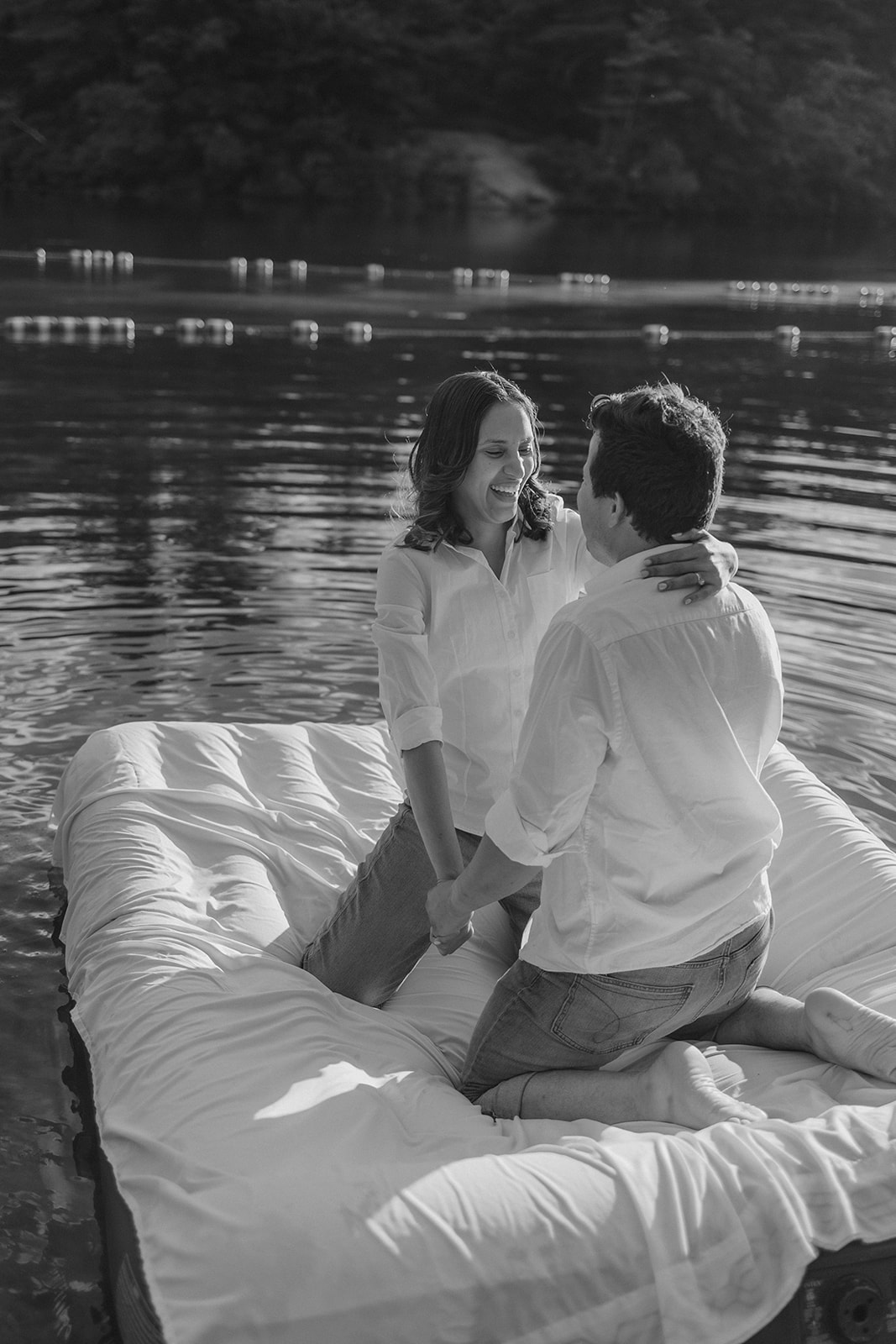 stunning couple pose on an air mattress floating on a lake during their fun New England engagement photoshoot