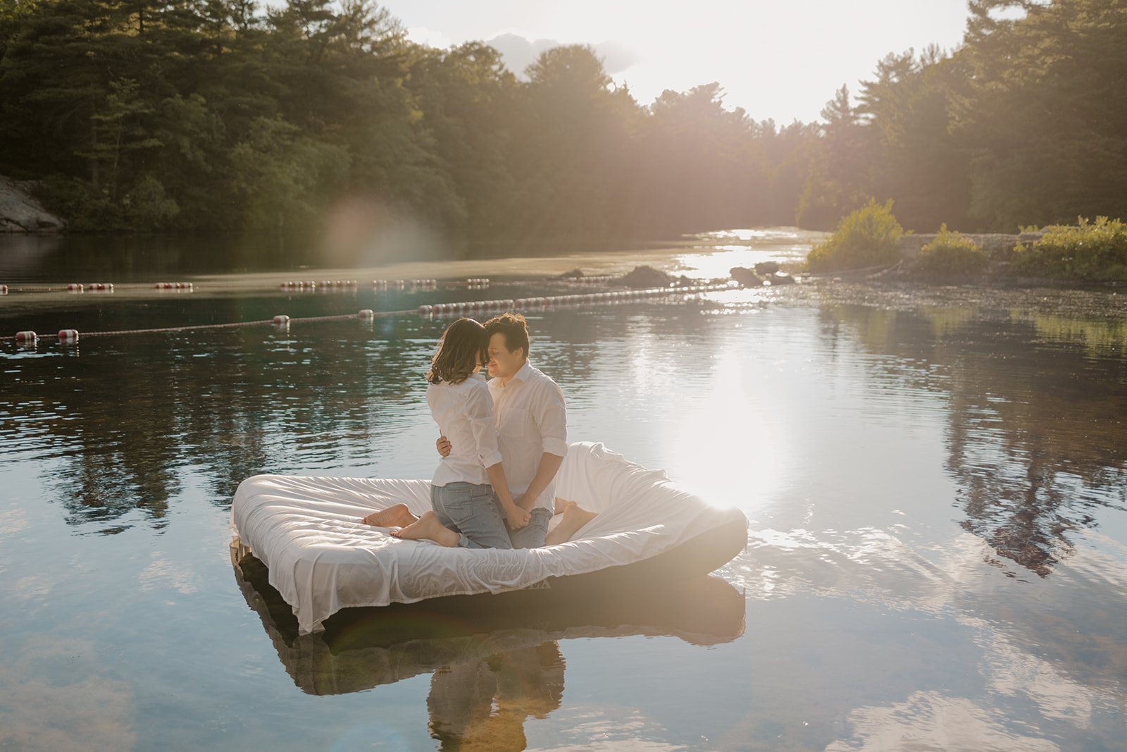 stunning couple pose on an air mattress floating on a lake during their fun New England engagement photoshoot