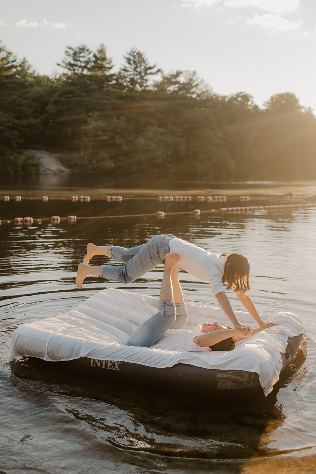 stunning couple pose on an air mattress floating on a lake during their fun New England engagement photoshoot