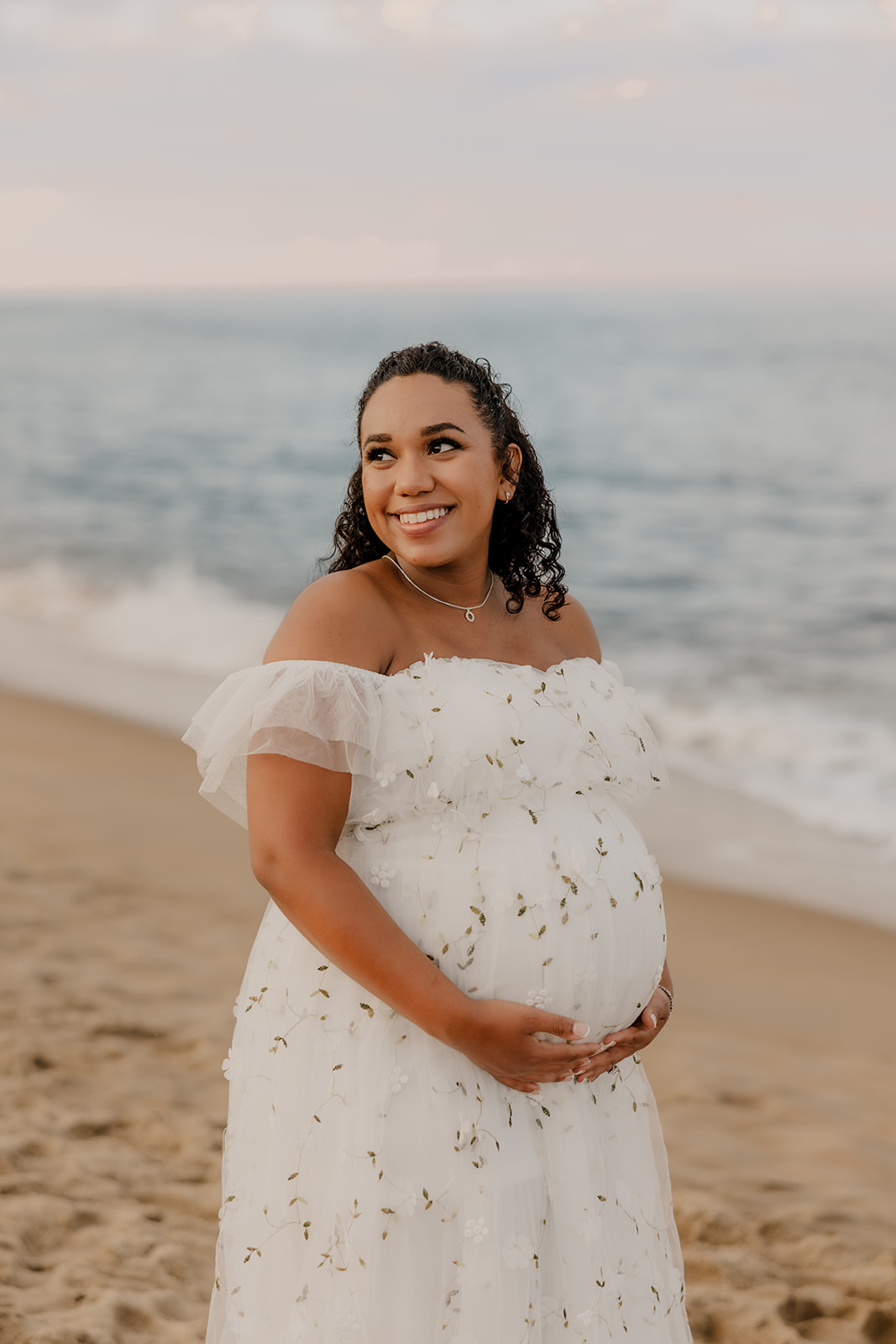 beautiful couple pose for their maternity photoshoot on an East Coast beach