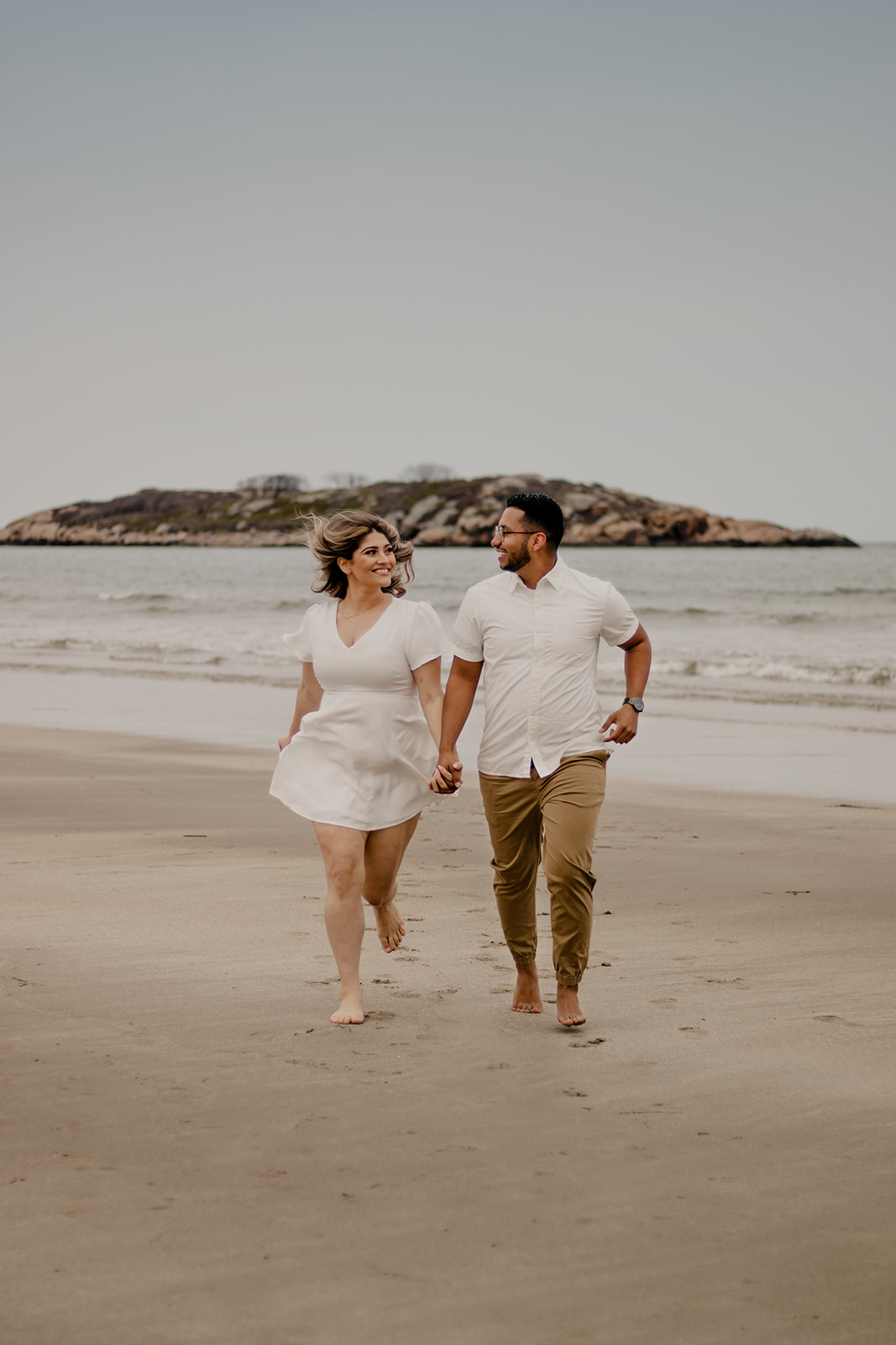 beautiful couple poses on a Boston beach for their dreamy engagement photo shoot