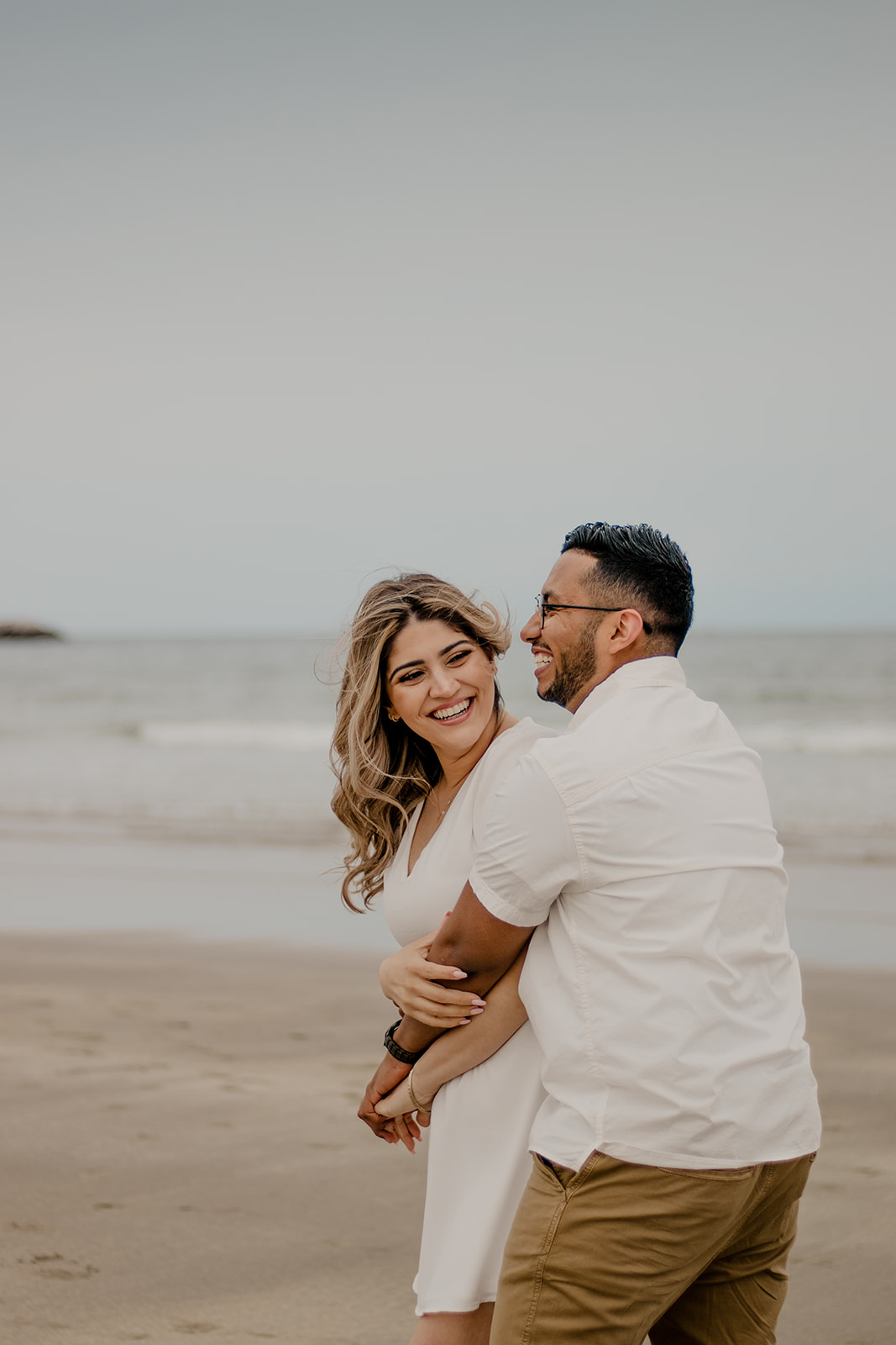 beautiful couple poses on a Boston beach for their dreamy engagement photo shoot