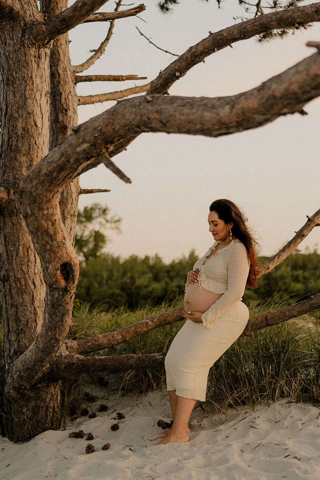 beautiful future mom sits on branch of an old tree