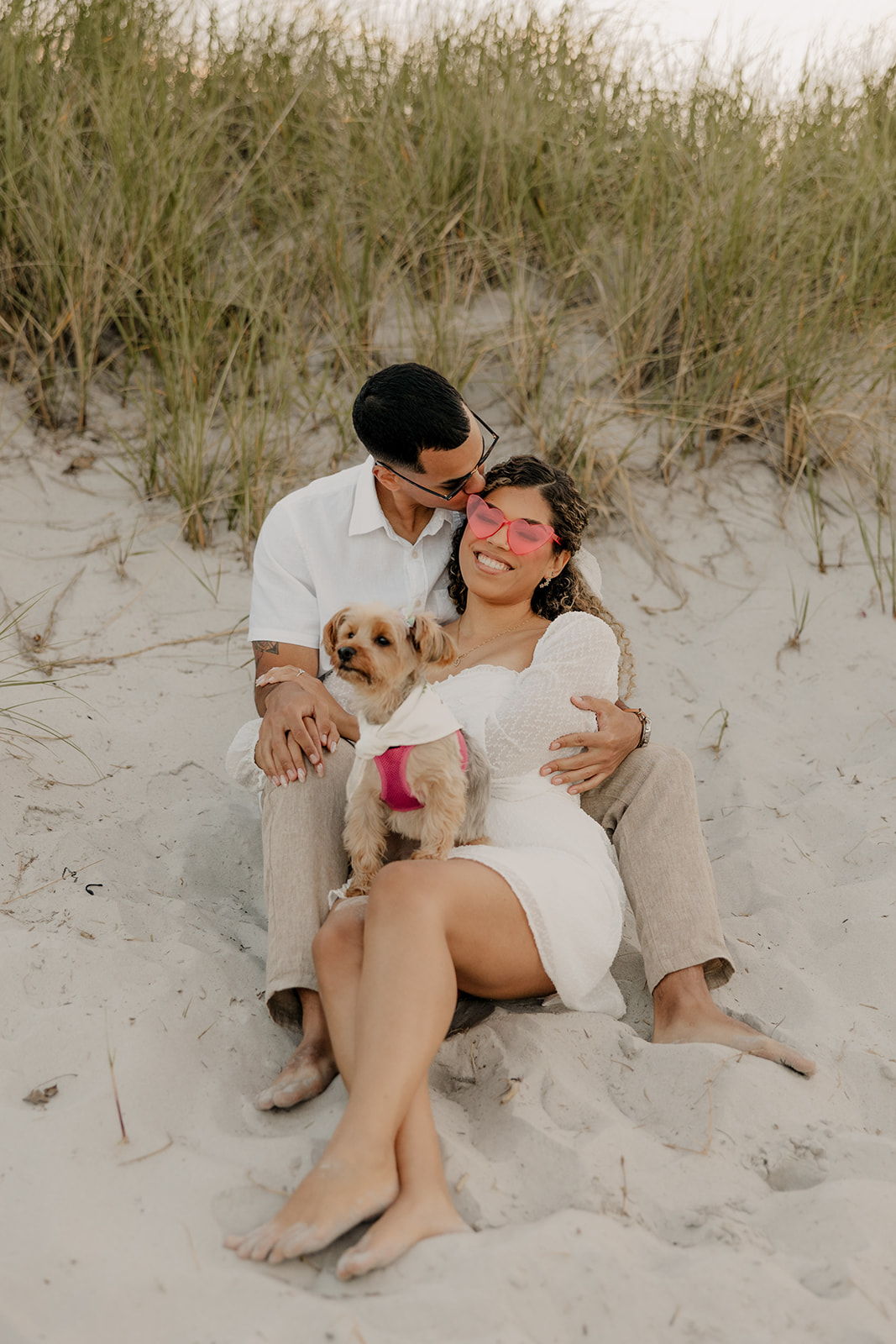 stunning couple pose with their dog during their beach engagement photoshoot