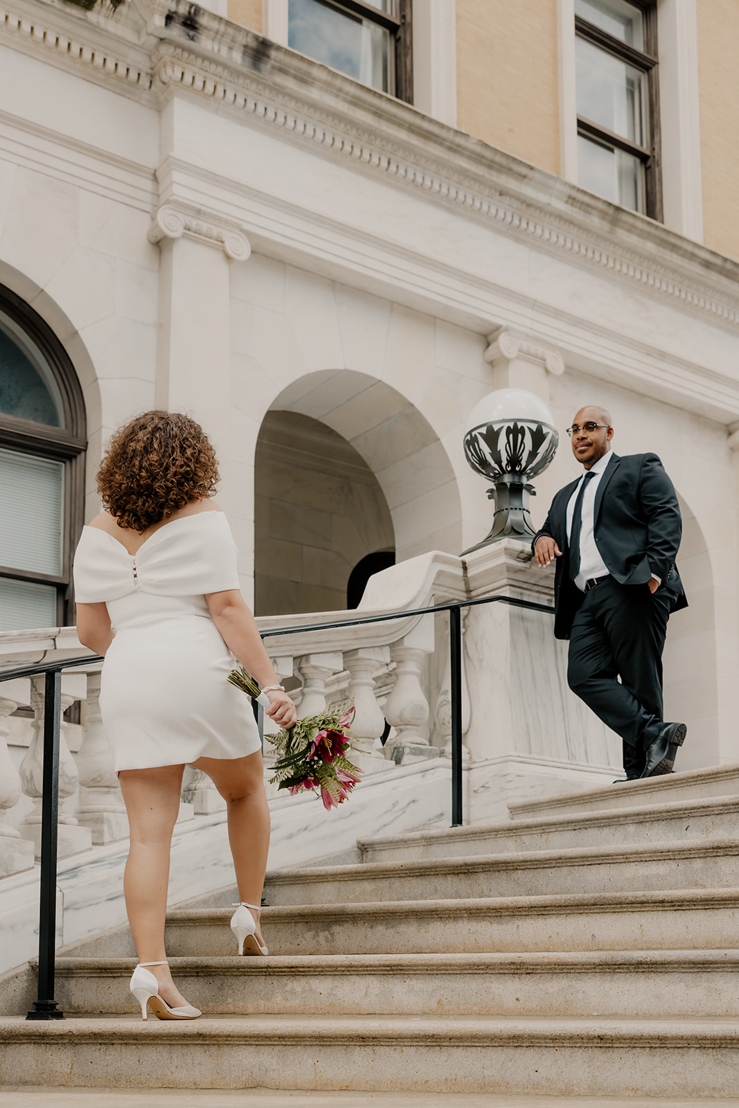 beautiful bride and groom stop for a picture on the stairs during their state house elopement