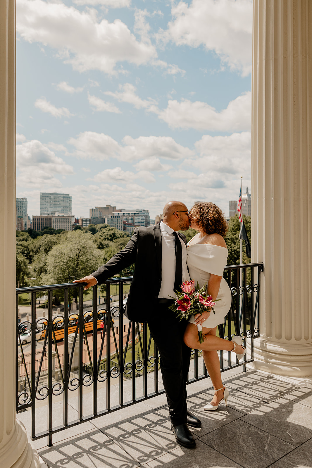 stunning bride and groom pose together on the state house balcony