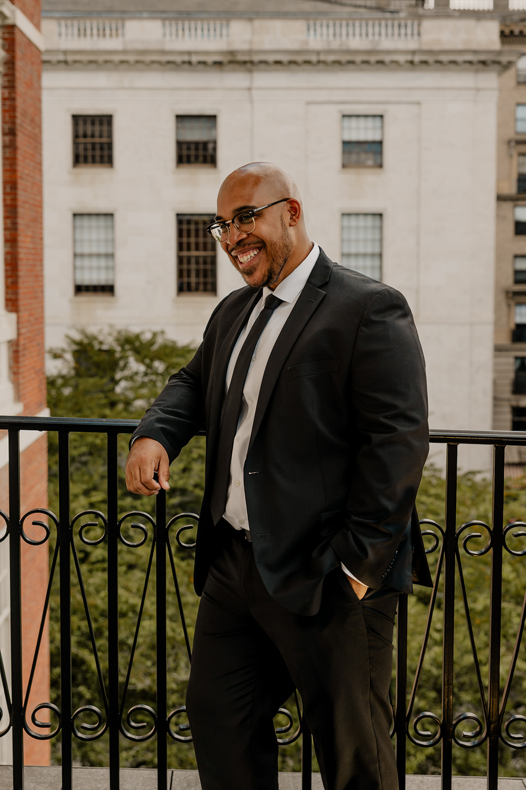 handsome groom poses on the state house balcony