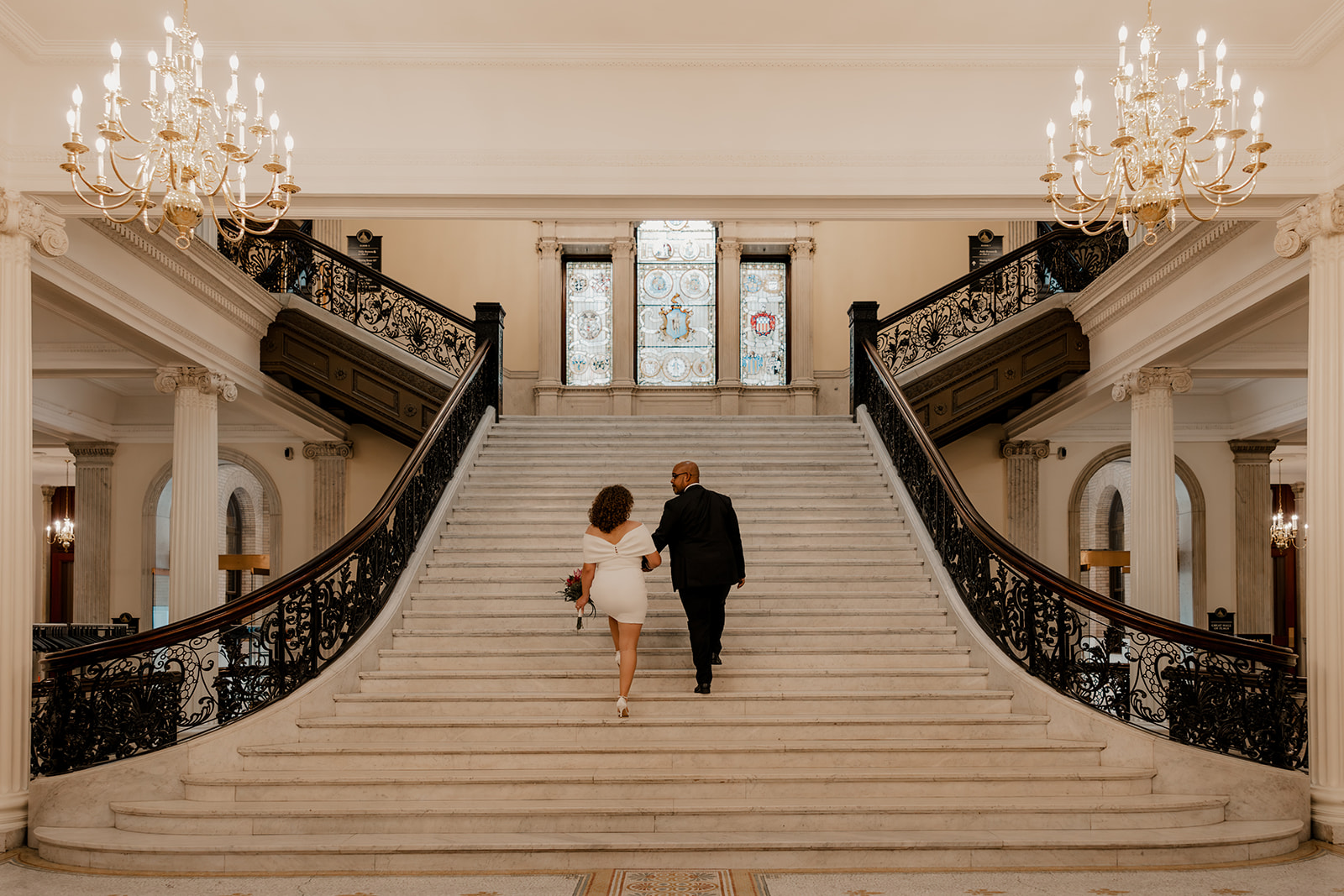 beautiful bride and groom stop for a picture on the stairs during their state house elopement